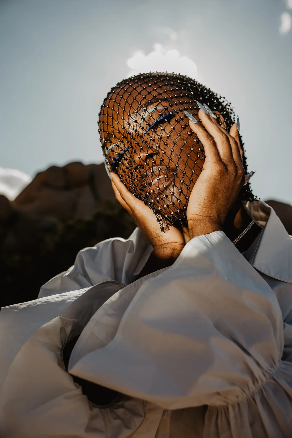Portrait in a beaded veil and flowing white sleeves