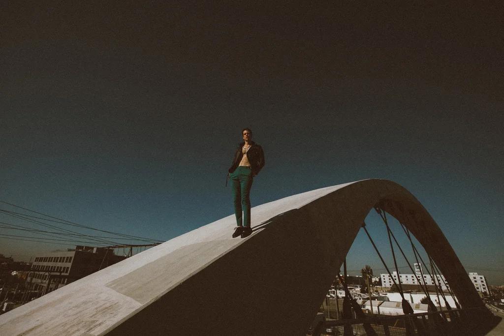A solitary figure standing on a sweeping concrete bridge